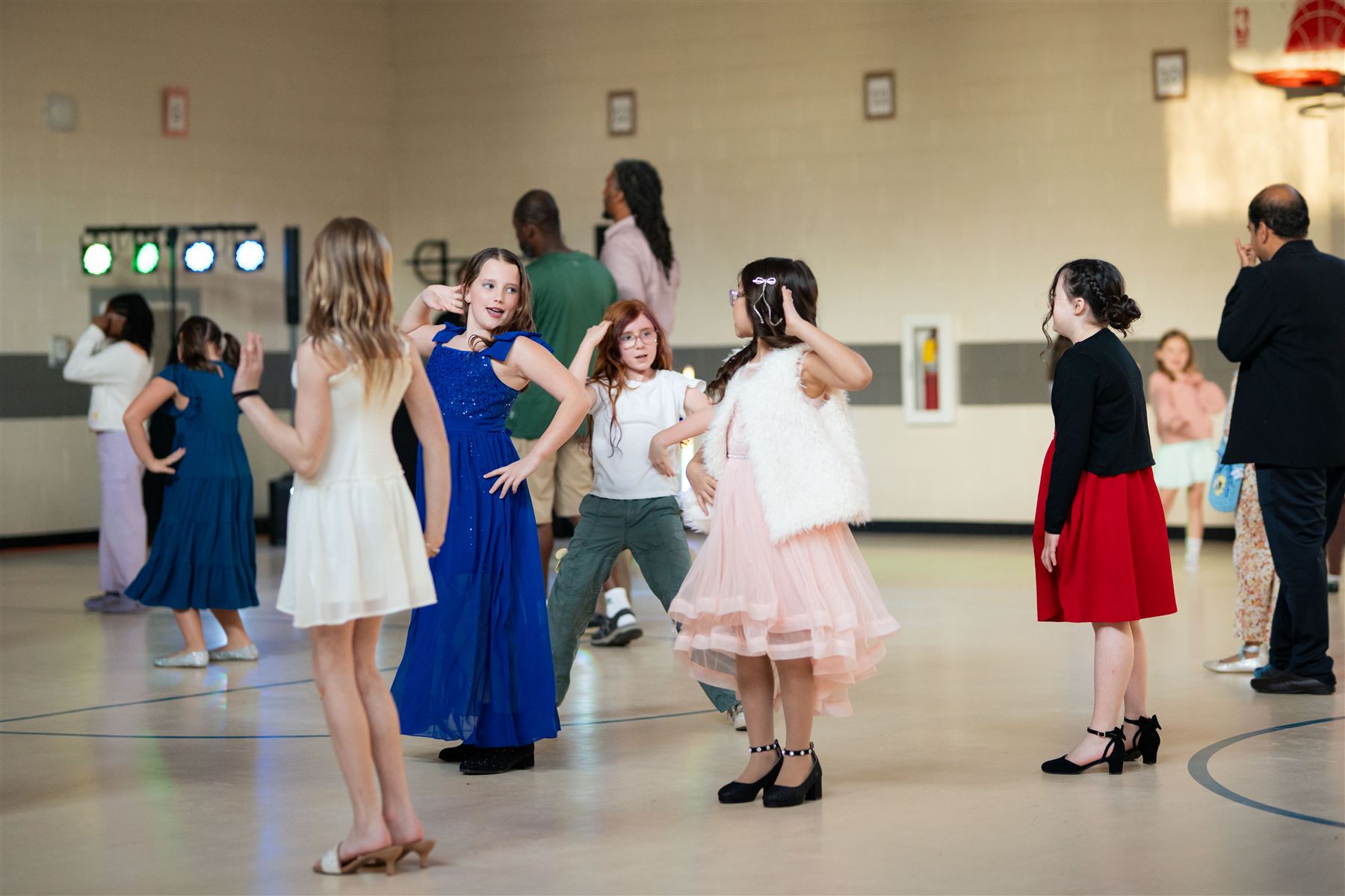 Kids and adults dancing together in a school gym at a father-daughter dance