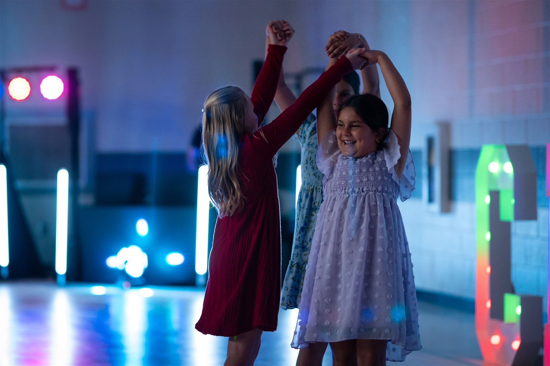 Two girls in dresses dancing together under blue and pink lights