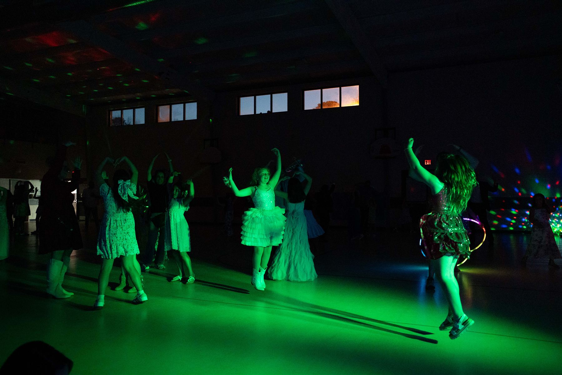 Girls dancing with their arms raised under green lights