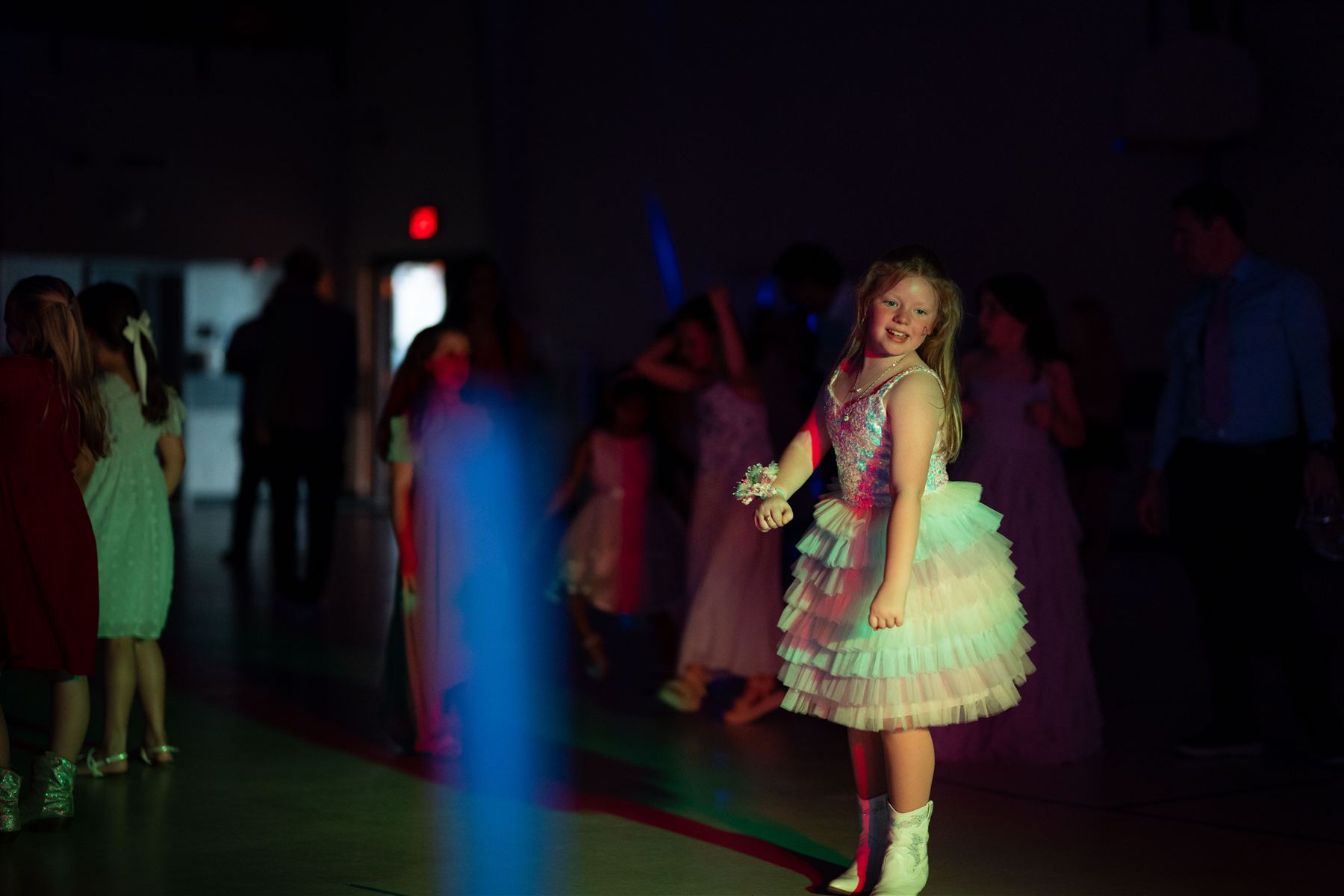 A girl in a sparkly dress smiling on the dance floor