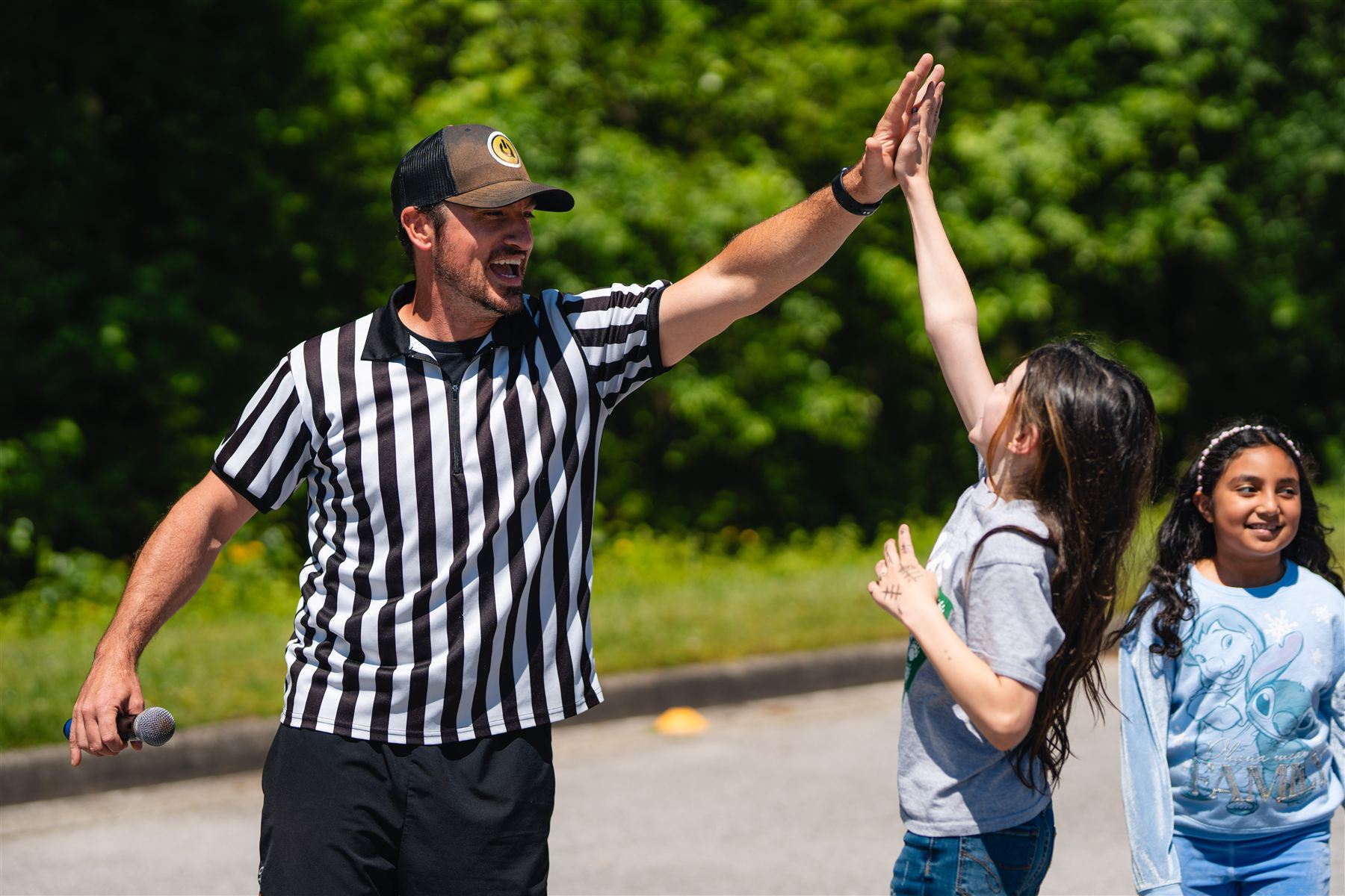 A referee-shirt emcee giving a high five to a student at a school fun run