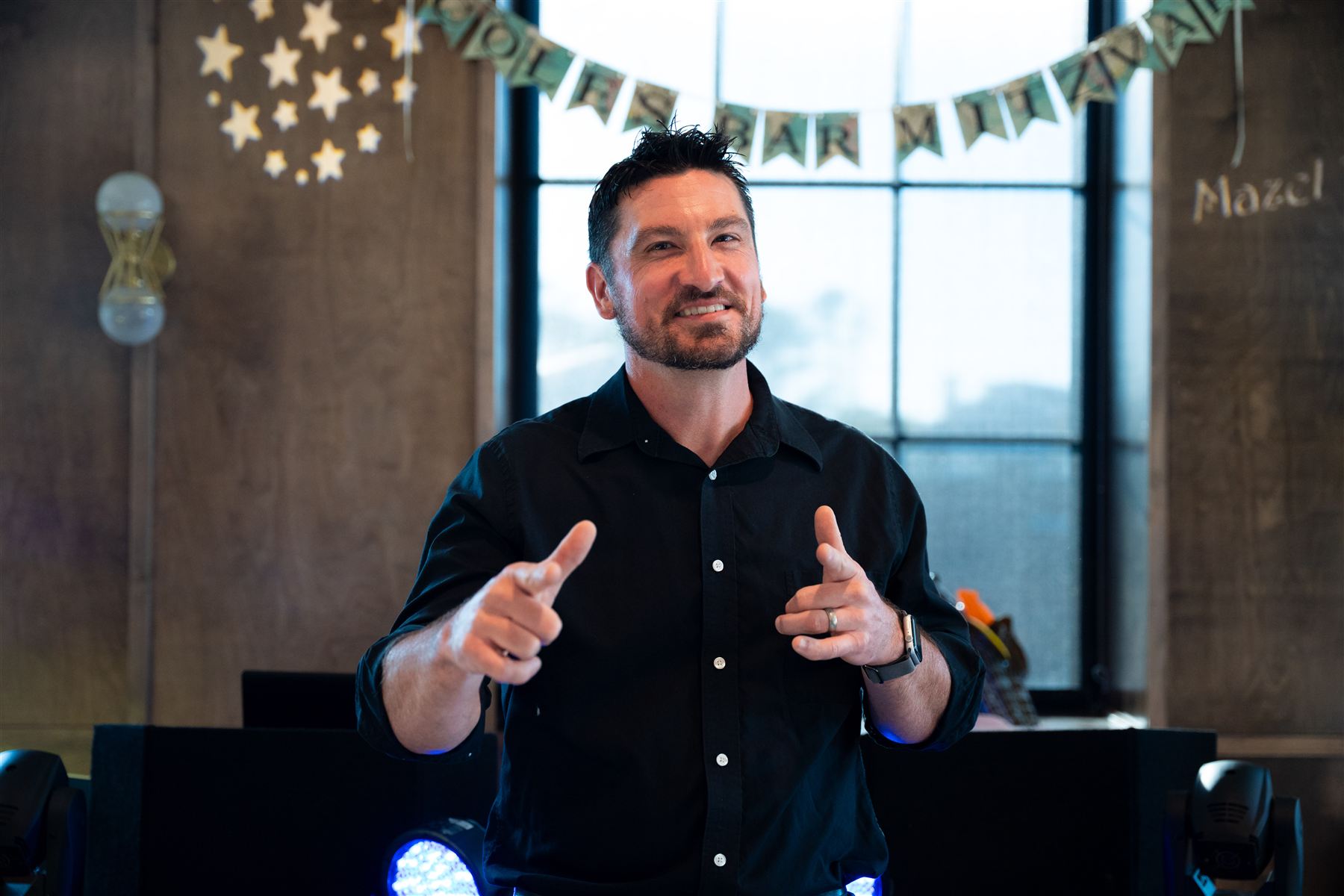 Brian, smiling and gesturing to the crowd at a party