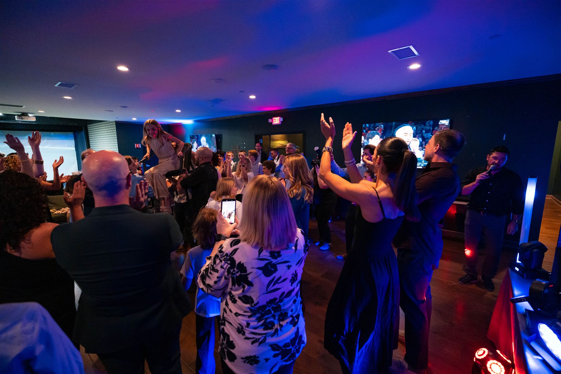 A crowd with hands in the air on a lit-up dance floor