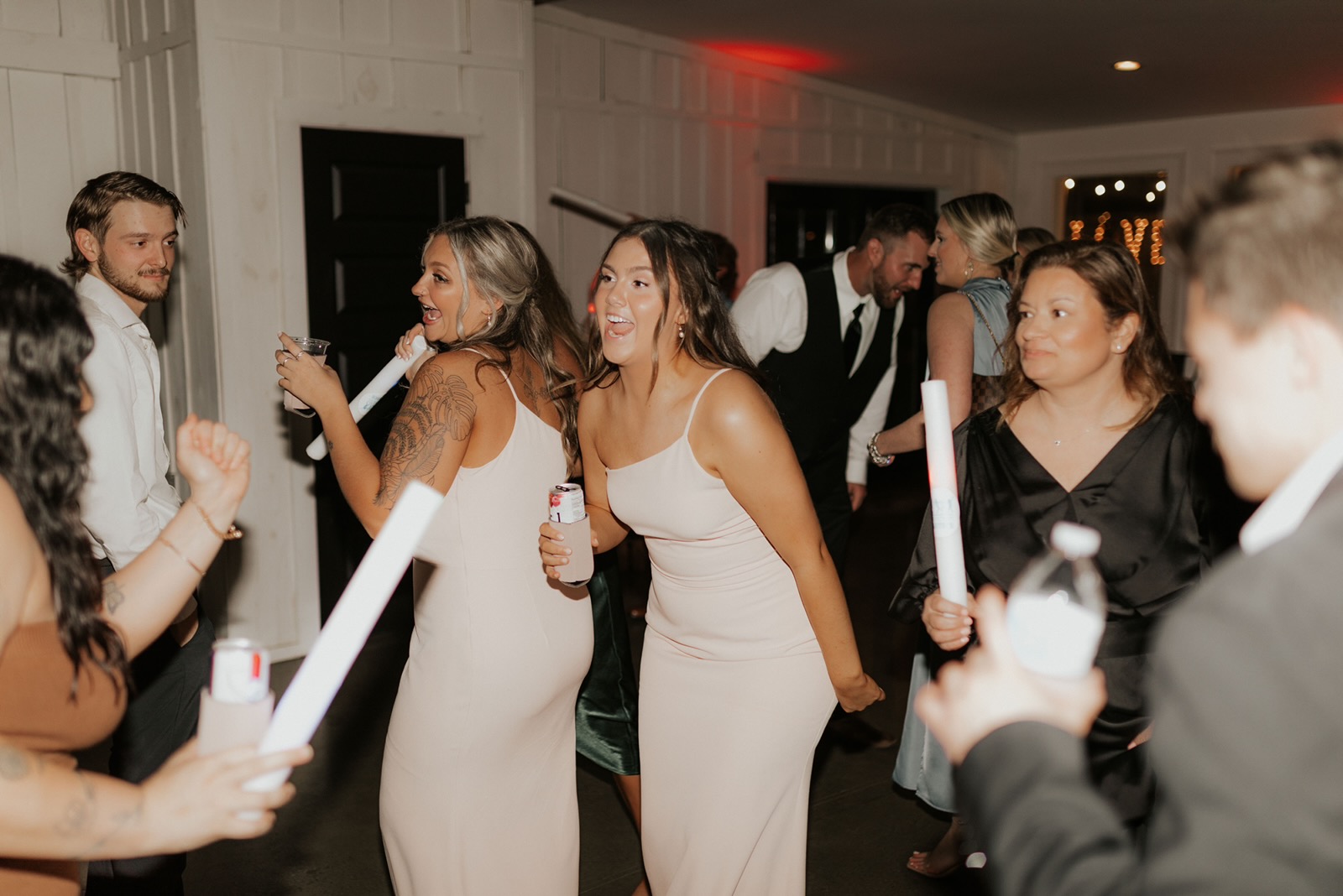 Bridesmaids laughing and dancing with glow sticks at a wedding reception
